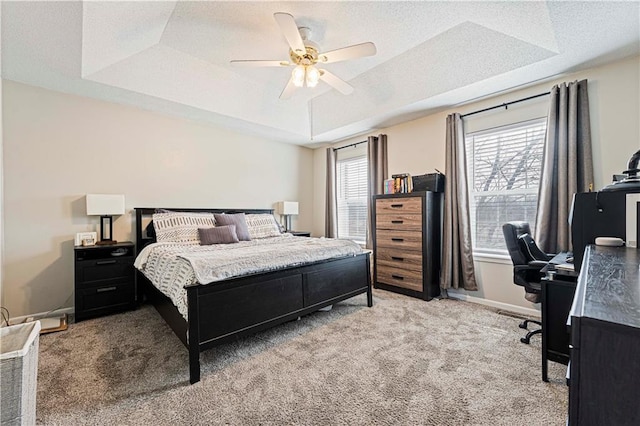 bedroom featuring a raised ceiling, light colored carpet, a textured ceiling, and baseboards