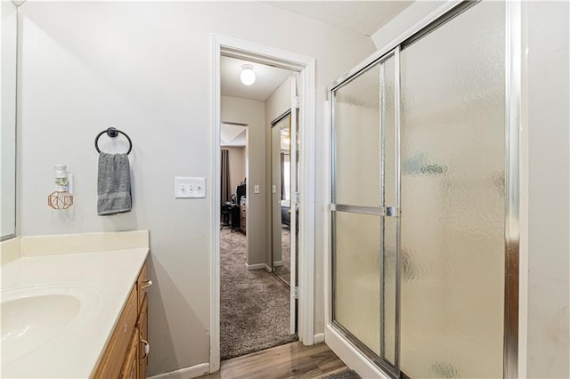 full bathroom with a stall shower, baseboards, wood finished floors, ensuite bathroom, and vanity