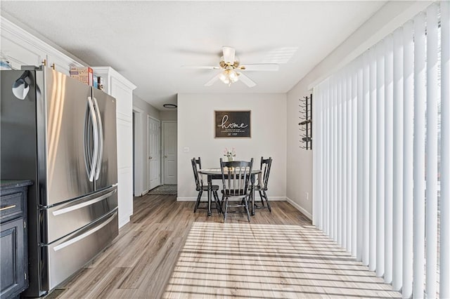 dining space with light wood-style floors, ceiling fan, and baseboards