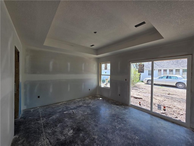 542 N Lexington St, Adrian, MO 64720 - spare room featuring a raised ceiling, a textured ceiling, and unfinished concrete floors