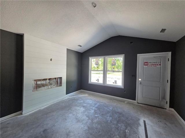 542 N Lexington St, Adrian, MO 64720 - unfurnished living room with a textured ceiling, vaulted ceiling, and unfinished concrete floors