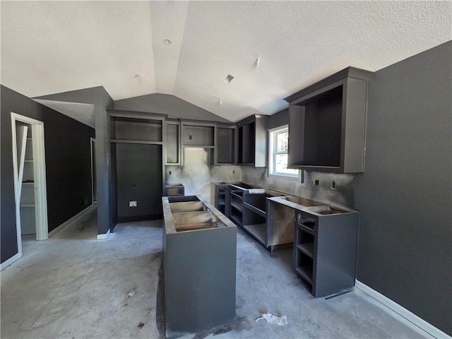 542 N Lexington St, Adrian, MO 64720 - kitchen with vaulted ceiling, baseboards, open shelves, and concrete flooring