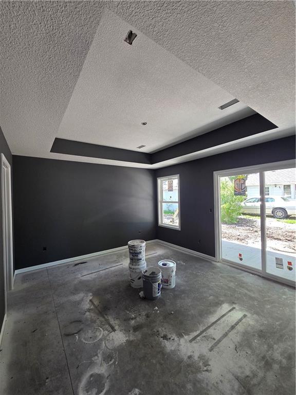 542 N Lexington St, Adrian, MO 64720 - unfurnished living room with a textured ceiling, baseboards, and a tray ceiling