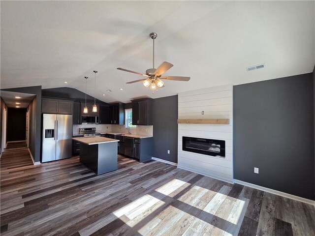 542 N Lexington St, Adrian, MO 64720 - kitchen featuring appliances with stainless steel finishes, lofted ceiling, light countertops, a kitchen island, and dark wood finished floors