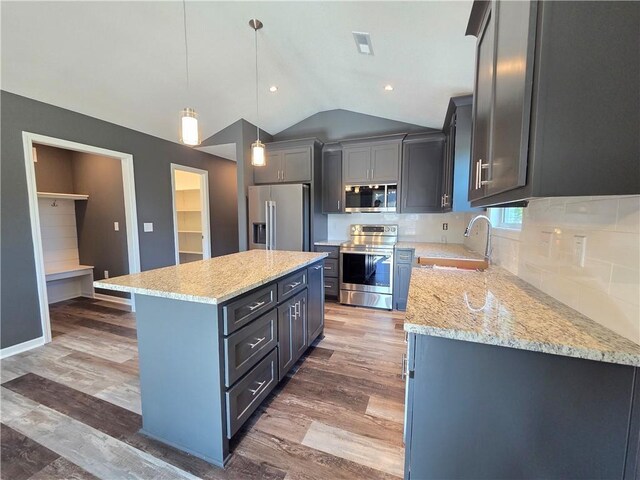 542 N Lexington St, Adrian, MO 64720 - kitchen featuring appliances with stainless steel finishes, a sink, vaulted ceiling, a kitchen island, and light stone countertops