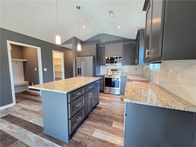 540 N Lexington St, Adrian, MO 64720 - kitchen featuring appliances with stainless steel finishes, a sink, vaulted ceiling, a kitchen island, and light stone countertops