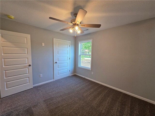 540 N Lexington St, Adrian, MO 64720 - unfurnished bedroom with dark colored carpet, baseboards, a textured ceiling, and ceiling fan