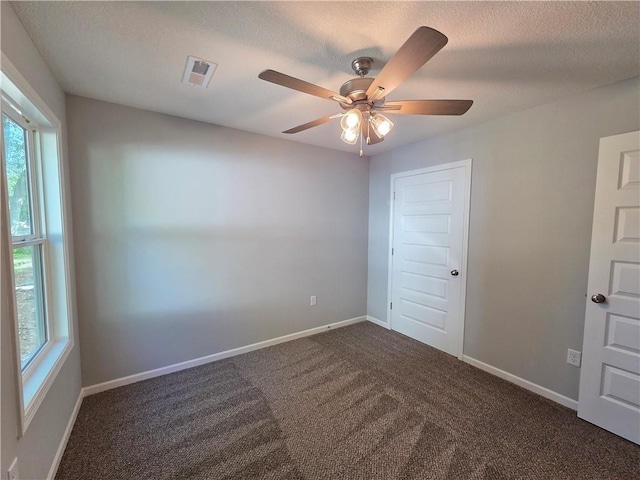 540 N Lexington St, Adrian, MO 64720 - spare room featuring healthy amount of natural light, dark carpet, ceiling fan, baseboards, and a textured ceiling
