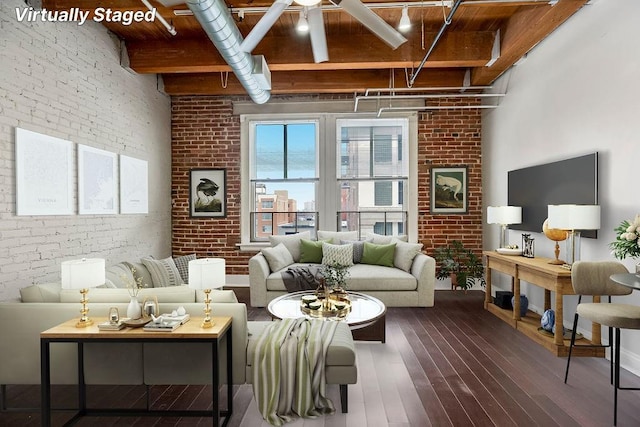 living area featuring beam ceiling, brick wall, and wood finished floors