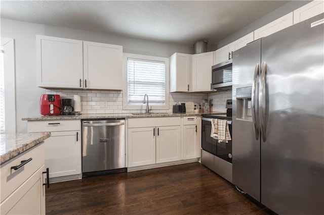 kitchen featuring stainless steel appliances, white cabinetry, a sink, and light stone countertops