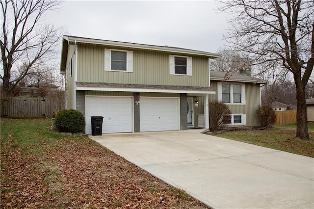 tri-level home featuring fence, driveway, and an attached garage