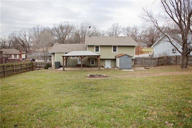 back of house featuring an outbuilding, an outdoor fire pit, a fenced backyard, a storage shed, and a gazebo