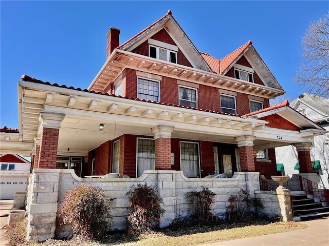 view of front of house featuring covered porch, a chimney, and brick siding