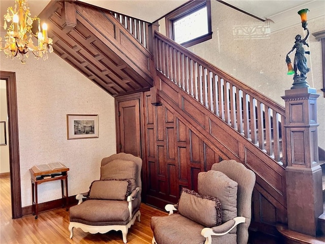 living area with vaulted ceiling, wood finished floors, stairs, and a notable chandelier