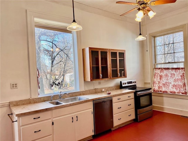 kitchen featuring white cabinets, appliances with stainless steel finishes, decorative light fixtures, light countertops, and a sink