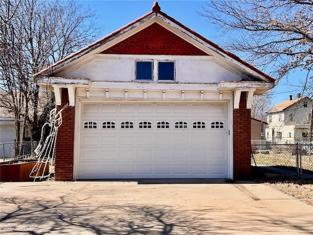 view of front facade featuring an outbuilding, brick siding, a detached garage, and fence