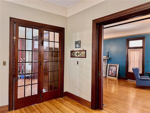 doorway featuring light wood finished floors, baseboards, ornamental molding, and french doors