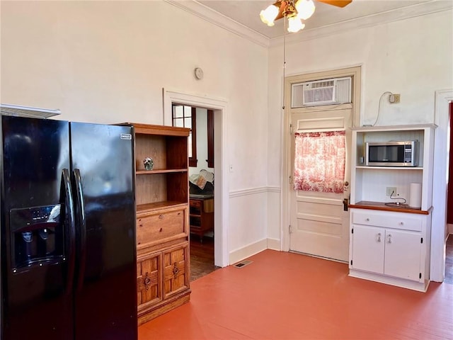 kitchen with crown molding, stainless steel microwave, black fridge with ice dispenser, visible vents, and an AC wall unit