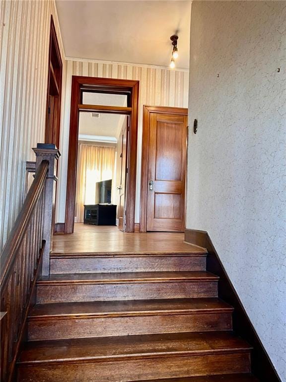 stairway with a textured wall and wood finished floors