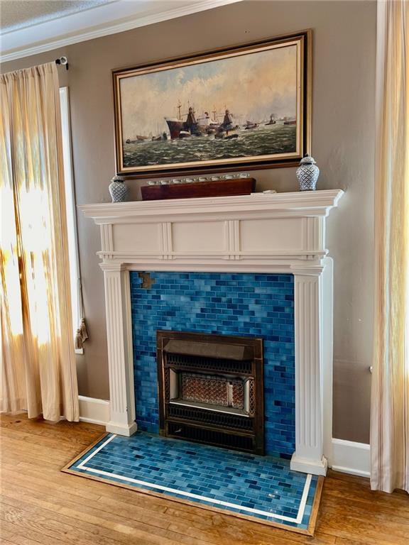 room details with ornamental molding, a fireplace, baseboards, and wood finished floors