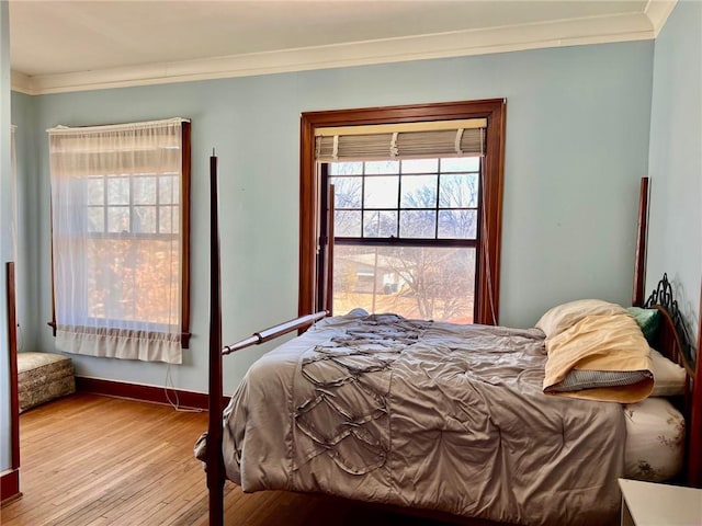 bedroom with ornamental molding, light wood-type flooring, and baseboards