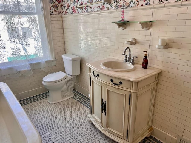 bathroom featuring toilet, tile patterned flooring, vanity, and tile walls