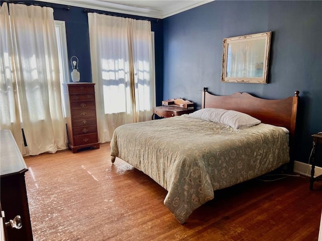 bedroom with crown molding and wood finished floors