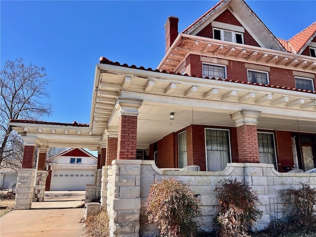 view of front of home with a chimney, a porch, and brick siding