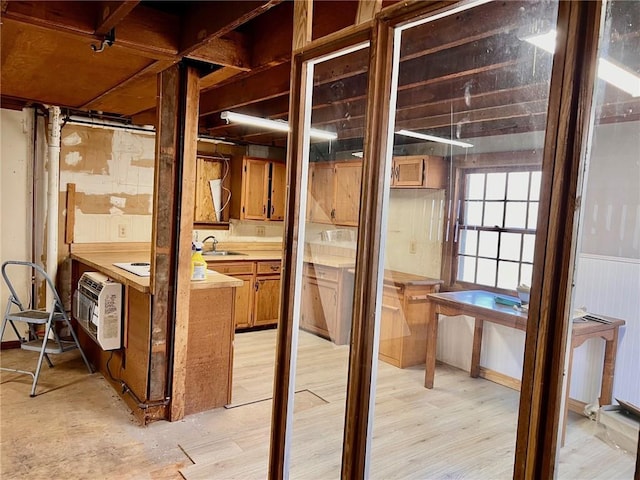 miscellaneous room featuring light wood-style floors, wainscoting, a sink, and heating unit