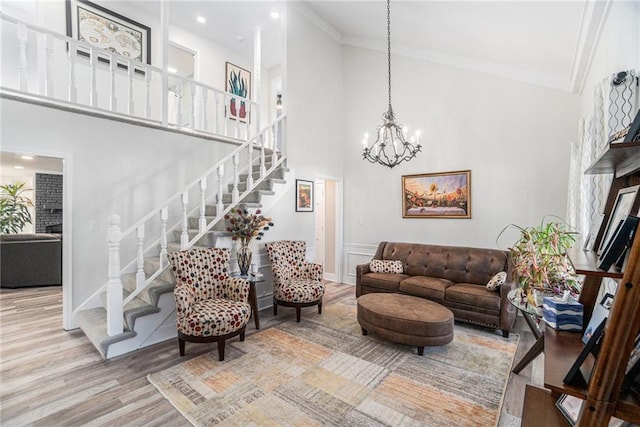 living room with a fireplace, a high ceiling, ornamental molding, wood finished floors, and stairs