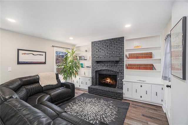 living area featuring dark wood-type flooring, recessed lighting, a fireplace, and built in features