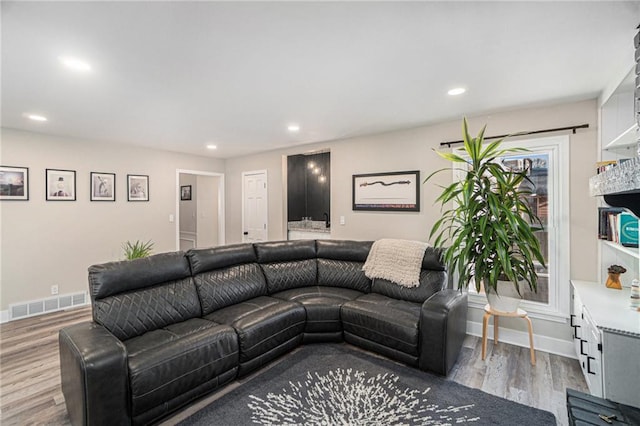 living area with baseboards, wood finished floors, visible vents, and recessed lighting