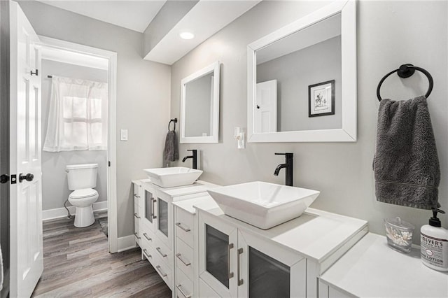 full bathroom with toilet, baseboards, a sink, and wood finished floors