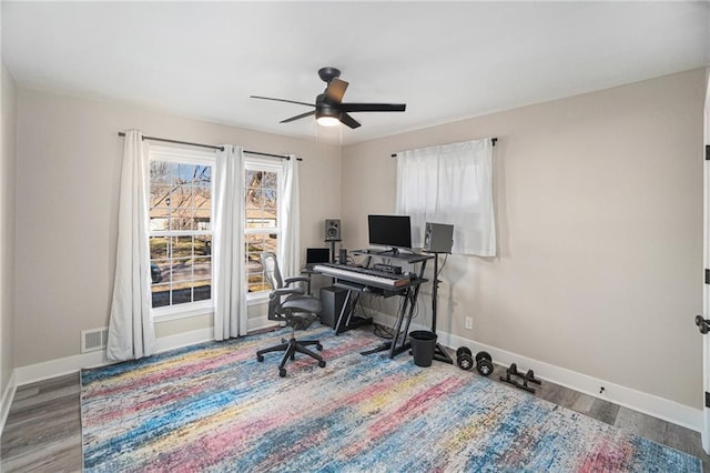 home office with a ceiling fan, wood finished floors, visible vents, and baseboards