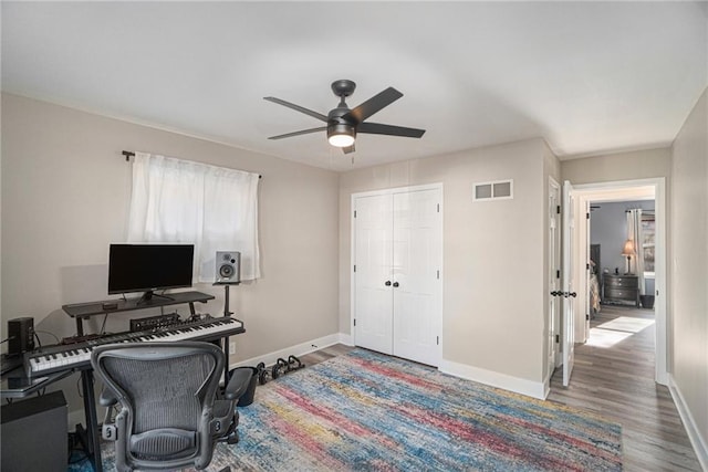 office area with baseboards, visible vents, ceiling fan, and wood finished floors