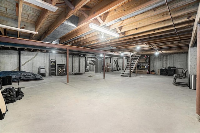 unfinished basement with water heater, stairway, and heating unit