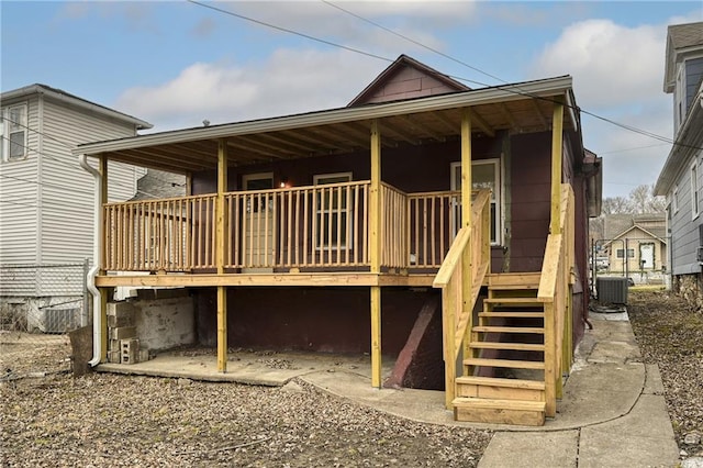 rear view of property with central air condition unit, stairs, and fence