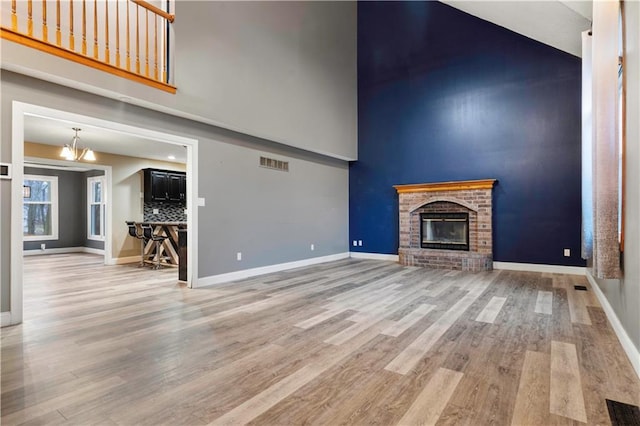 unfurnished living room with baseboards, a fireplace, visible vents, and wood finished floors