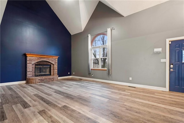 unfurnished living room featuring high vaulted ceiling, wood finished floors, visible vents, baseboards, and a brick fireplace