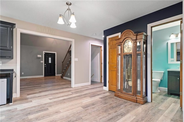 interior space featuring baseboards, light wood-style flooring, stairway, a textured ceiling, and a chandelier