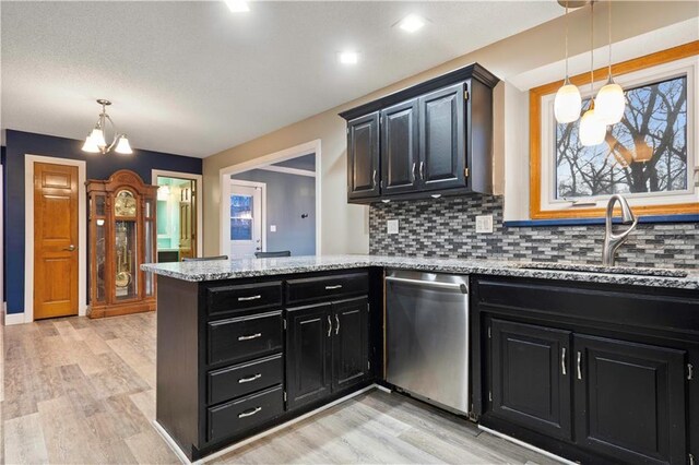 kitchen featuring a peninsula, dark cabinets, a sink, and dishwasher