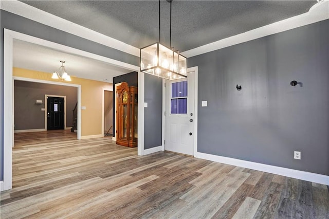 unfurnished dining area featuring baseboards, a chandelier, and wood finished floors