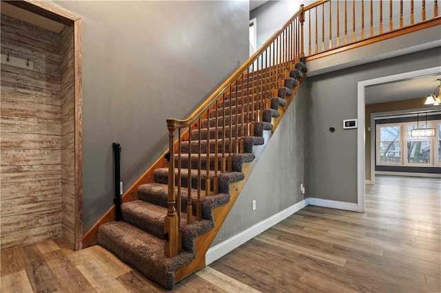 stairs with a towering ceiling, baseboards, and wood finished floors