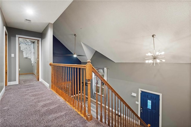 corridor featuring carpet flooring, an upstairs landing, baseboards, visible vents, and an inviting chandelier