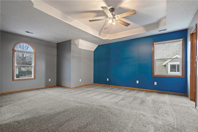 spare room featuring a tray ceiling, visible vents, and baseboards