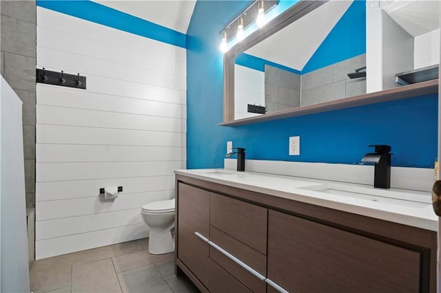 full bathroom featuring toilet, tile patterned flooring, double vanity, and a sink