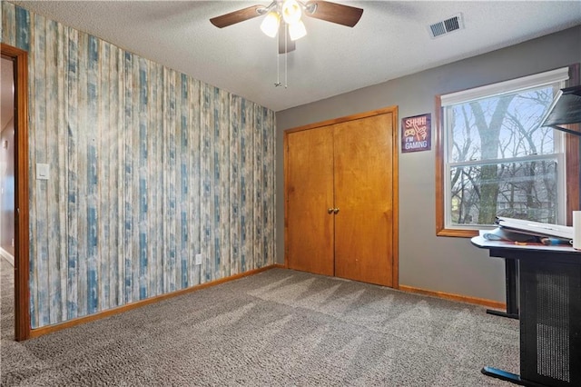 unfurnished bedroom featuring a textured ceiling, visible vents, baseboards, carpet, and wallpapered walls