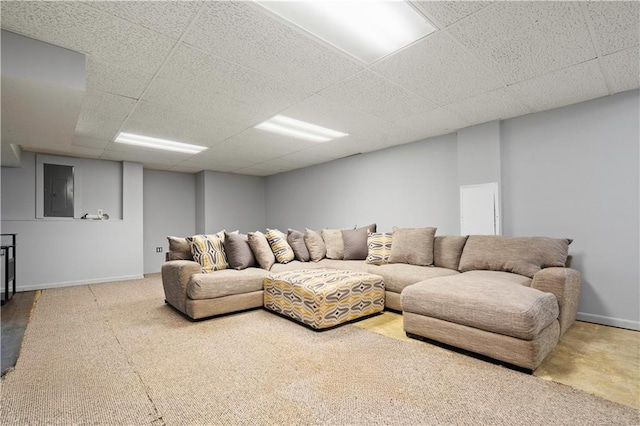 living room featuring baseboards and a drop ceiling