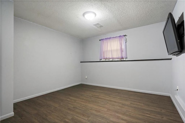 empty room with visible vents, a textured ceiling, baseboards, and wood finished floors