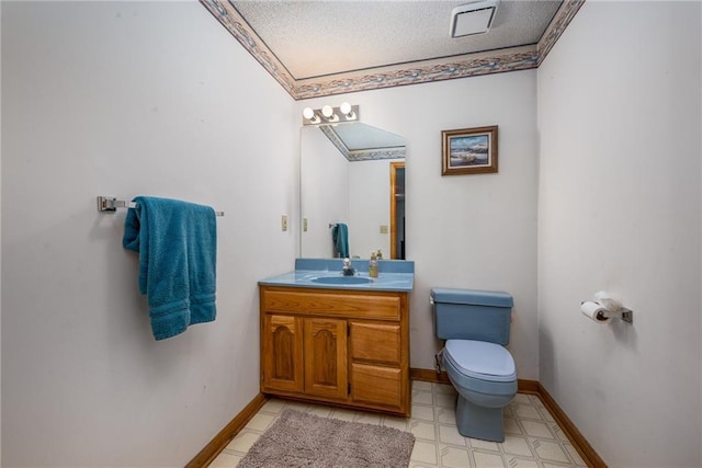 bathroom with toilet, a textured ceiling, vanity, and baseboards